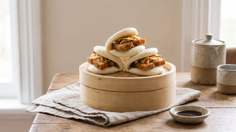 Fluffy steamed hirata bao buns stacked on a bamboo steamer