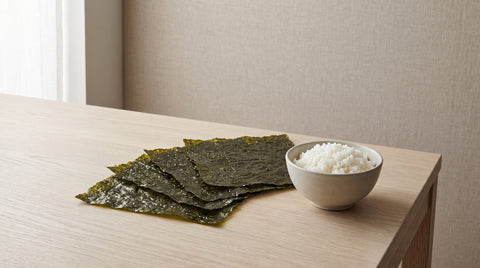 Sheets of premium dark green nori beside a bowl of rice