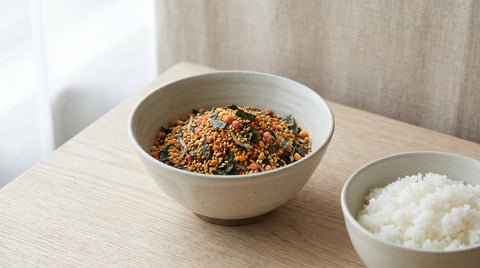 Bowl of colourful furikake rice seasoning beside a bowl of rice