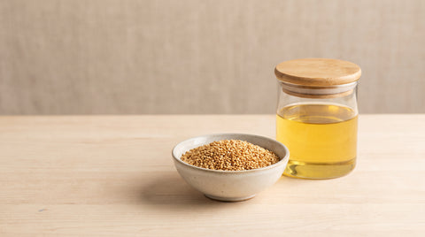 Toasted sesame seeds beside a jar of sesame oil