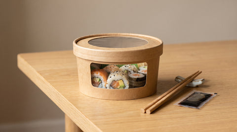 Sushi in a takeaway kraft box with chopsticks and soy sauce
