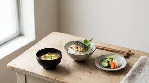 Three small healthy Japanese dishes including miso soup and grilled fish