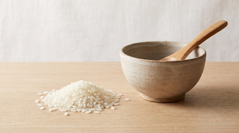 Fresh sushi-grade rice grains beside a bowl for cooking