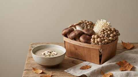 Fresh Japanese mushrooms in a wooden basket beside mushroom soup