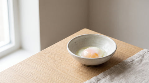A delicate onsen egg with a soft runny yolk in a small bowl, editorial food photography