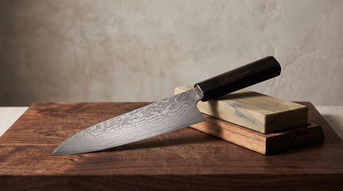 Elegant Japanese kitchen knife on a cutting board with whetstone