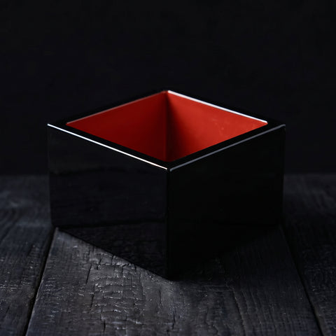 Fukui black and vermilion masu sake cup on charred wood
