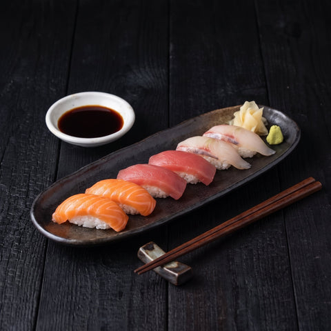 Nigiri sushi with a white dish of Kōmi Artisan soy sauce for dipping, serve view