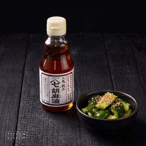Kuki, Classic Roast Sesame Oil, 170g, beside a bowl of sesame cucumber salad