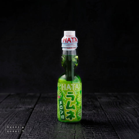 Hatakosen Melon Ramune 200ml, bottle on charred shou sugi ban wood against a black background