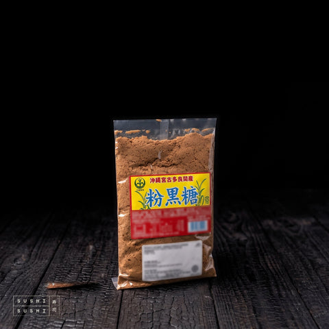 Kokuto, Okinawan Powdered Brown Sugar, 270g, bag on charred shou sugi ban wood against a black background