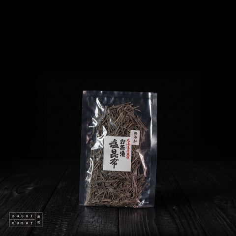 Kōmi, Salted Kombu (Shio-Kombu), Additive-Free, 50g, clear pack on charred shou sugi ban wood against a black backdrop