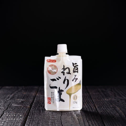 Mitake, Roasted White Sesame Paste, 120g, pouch on a charred shou sugi ban wooden surface against a black background