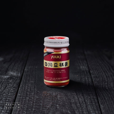 Youki, Tobanjan Chilli Bean Paste, 130g, jar on charred wood