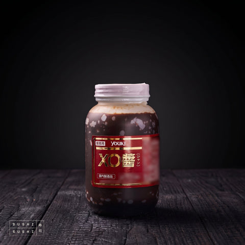 Youki XO Sauce 1Kg, jar on charred shou sugi ban wood against a black backdrop